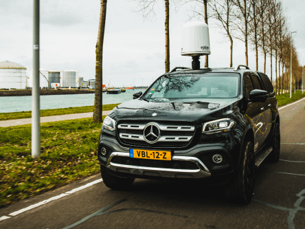 A black Mercedes 4x4 driving along a tree-lined road with IRIS drone detection radar mounted on the roof